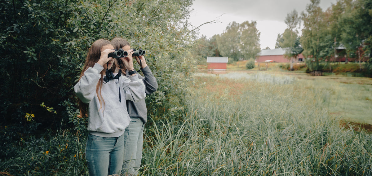 To jenter med kikkert i naturreservat.